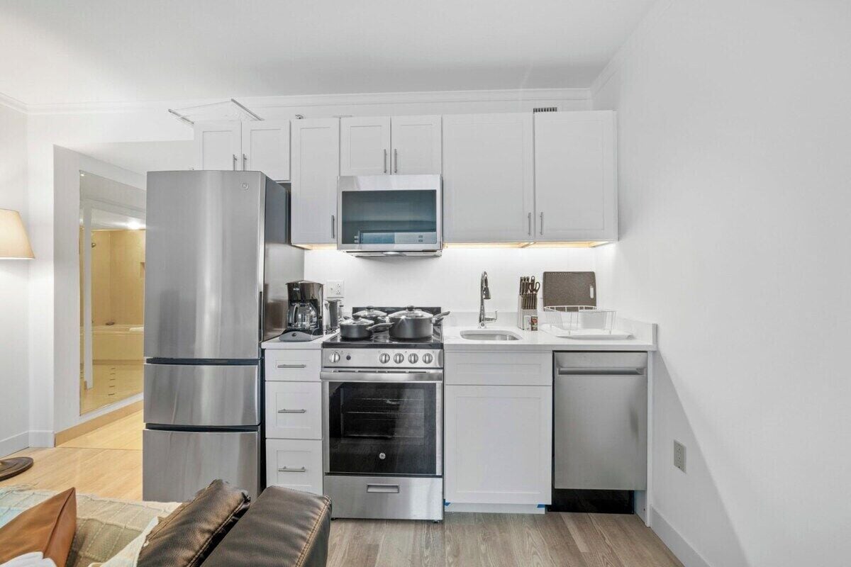A compact kitchen with a refrigerator, stove, oven, microwave, and sink.