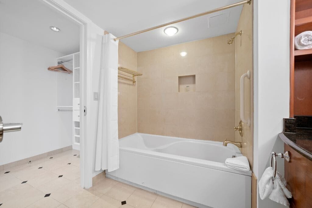 Ein modernes Badezimmer mit Badewanne, Dusche und begehbarem Kleiderschrank.