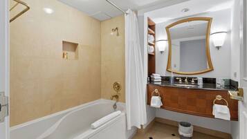 Uma casa de banho moderna com banheira, chuveiro, espelho sobre a pia e um porta-toalhas.