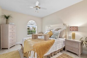 Une chambre à coucher comprenant un lit, une commode, une table de chevet et un ventilateur de plafond.