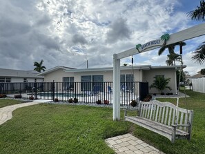 Ein Wohnhaus mit Swimmingpool, einer Holzbank und einem Schild mit der Aufschrift 'Beach House'.