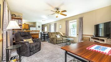 A living room with a sofa, two armchairs, a TV, and a dining area with a table and chairs.