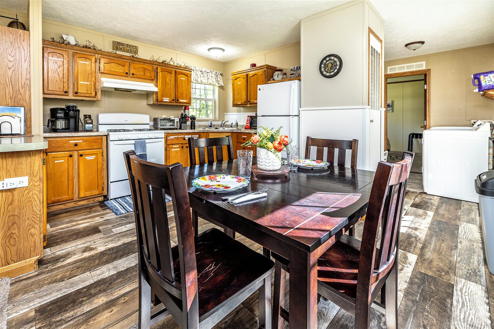 A kitchen with wooden cabinets, a dining table with chairs, and a refrigerator.