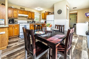 A kitchen with wooden cabinets, a dining table with chairs, and a refrigerator.