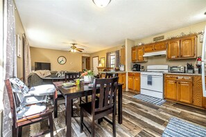 A compact kitchen with wooden cabinets, a stove, and a dining area with a table and chairs.