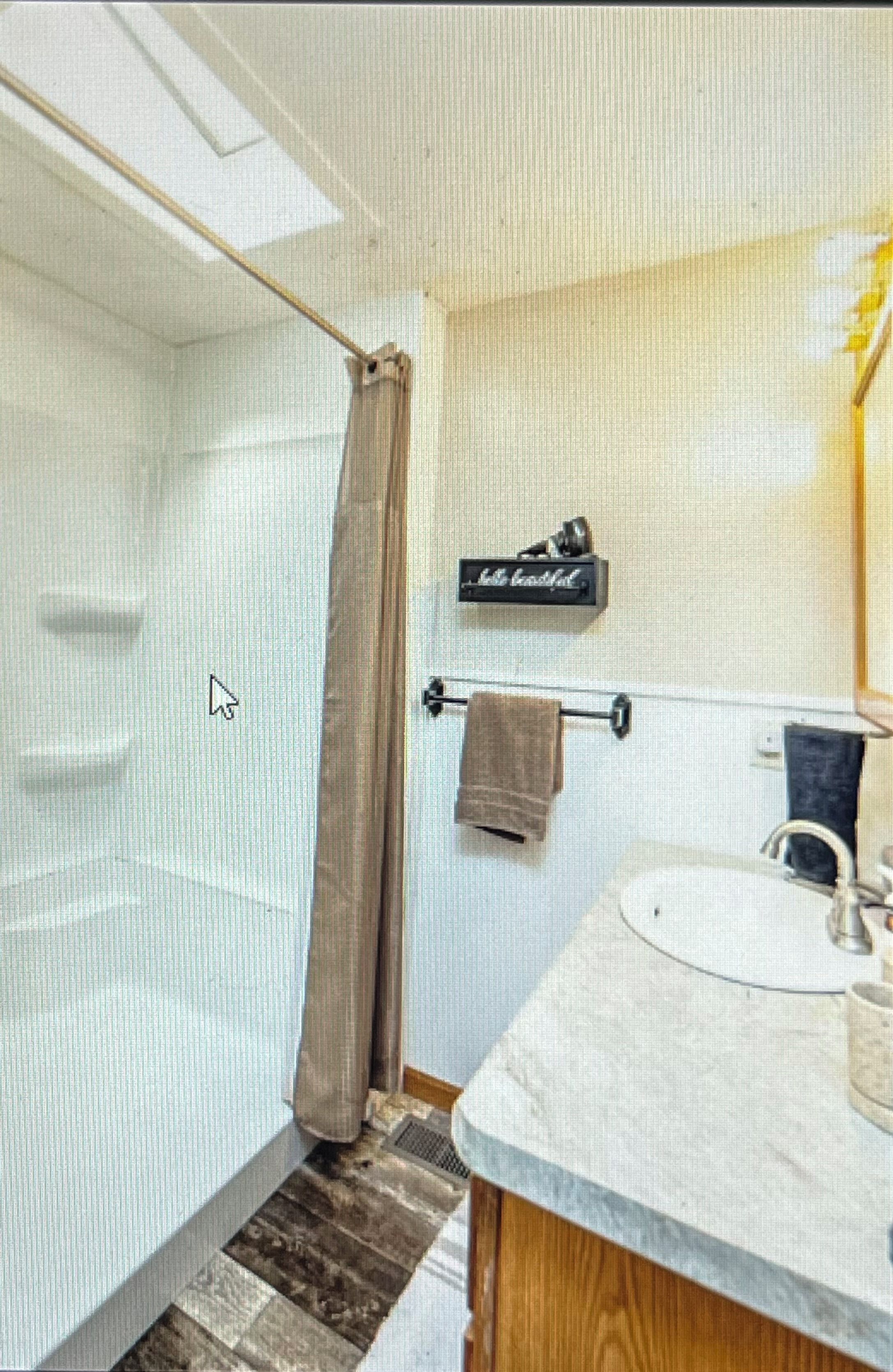 A bathroom with a shower, a towel rack, and a sink.