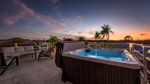 A rooftop terrace with a hot tub, outdoor seating, and a view of the sunset. - Beautiful fully gated private home with resort like amenities (Noord)
