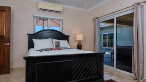 A bedroom with a large bed, a window with a view, an air conditioning unit, and a sliding glass door to a balcony. - Beautiful fully gated private home with resort like amenities (Noord)