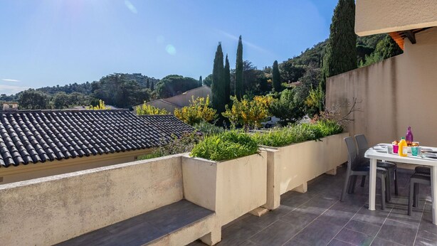 A rooftop terrace with a dining table and chairs, surrounded by planters and a view of the countryside. - Nice apartment for 4 people with WIFI, pool, TV and terrace (Le Lavandou)