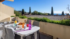 A table set outdoors with a view of a vineyard and distant buildings. - Nice apartment for 4 people with WIFI, pool, TV and terrace (Le Lavandou)