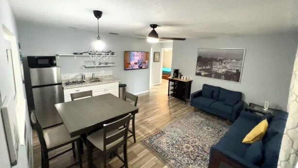 A compact living space with a dining area, kitchen, and a seating area with a sofa and a rug.