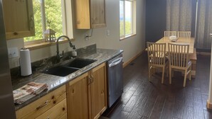 A kitchen with wooden cabinets, a granite countertop, a sink, and a dining area with a table and chairs.