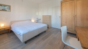 Ein Schlafzimmer mit Bett, Nachttisch, Kommode und einem Holzschrank.