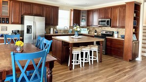 Une cuisine moderne avec des meubles en bois, un réfrigérateur en acier inoxydable, un four à micro-ondes et un îlot central doté de tabourets.