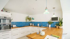 A modern kitchen with white cabinets, blue backsplash, wooden countertop, and a built-in oven. - Seashells - 4 Bed - 2 Bath - Nr Beach - Sleeps 7 (Isle of Wight)