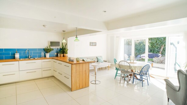 A bright kitchen with white cabinets, a wooden countertop, and a dining area with a table and chairs. - Seashells - 4 Bed - 2 Bath - Nr Beach - Sleeps 7 (Isle of Wight)