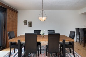 A dining room with a wooden table, black chairs, a hanging light fixture, and a patterned rug. - Cozy Condo, Hot Tub, Pool, Hiking/Fishing Close! (Durango)