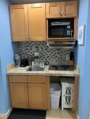 Compact kitchen with an oven, microwave, and sink.