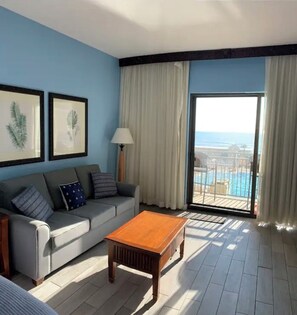 Relax in comfort with a sofa, coffee table, and balcony access to pool views.