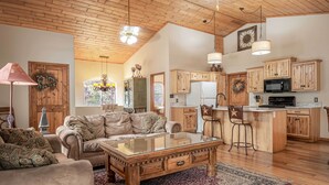A spacious living room with a large sofa, a glass coffee table, and a wooden ceiling.