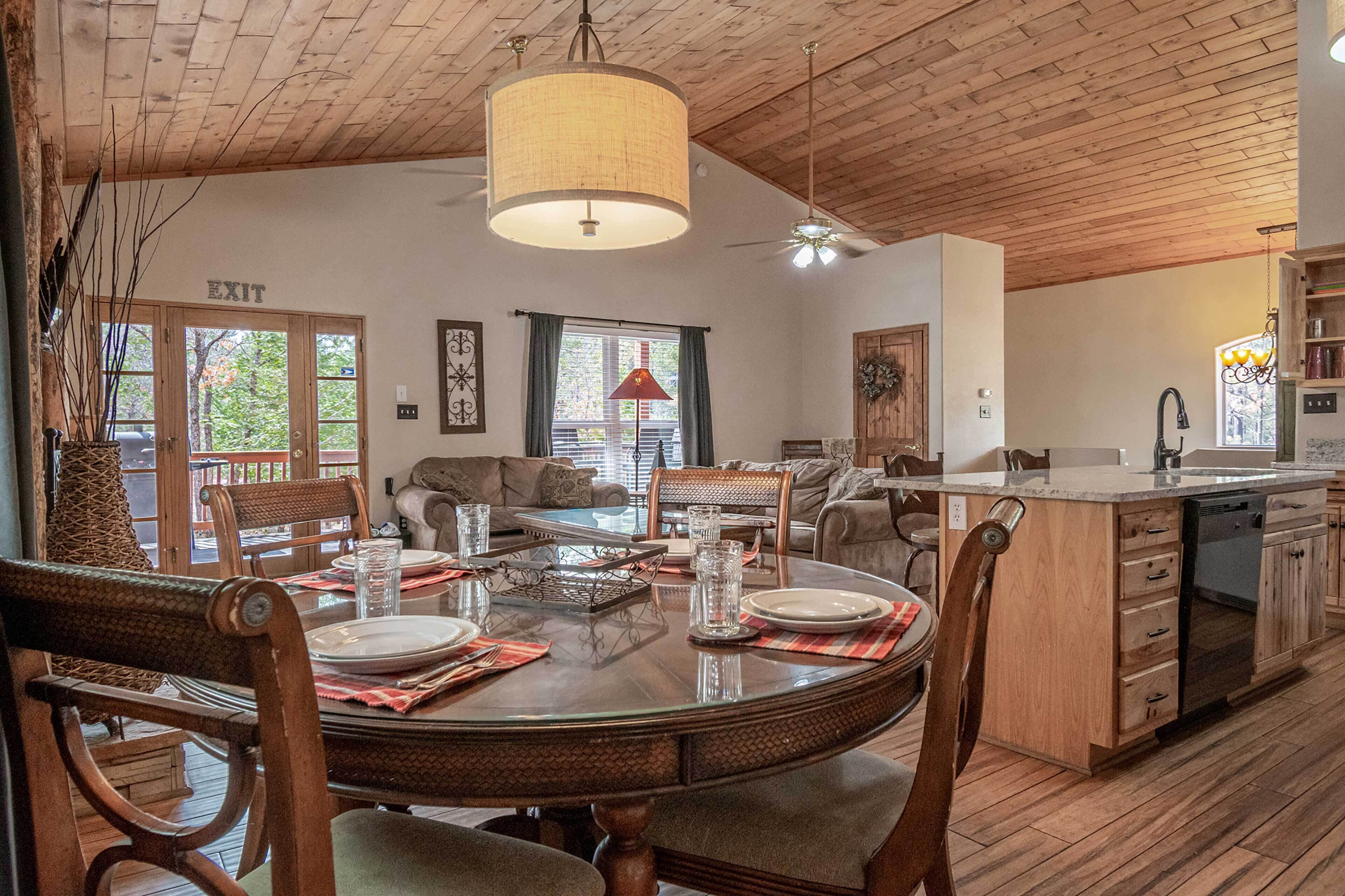 Un comedor amplio con una mesa y sillas de madera, una cocina con armarios de madera, y un letrero de salida.