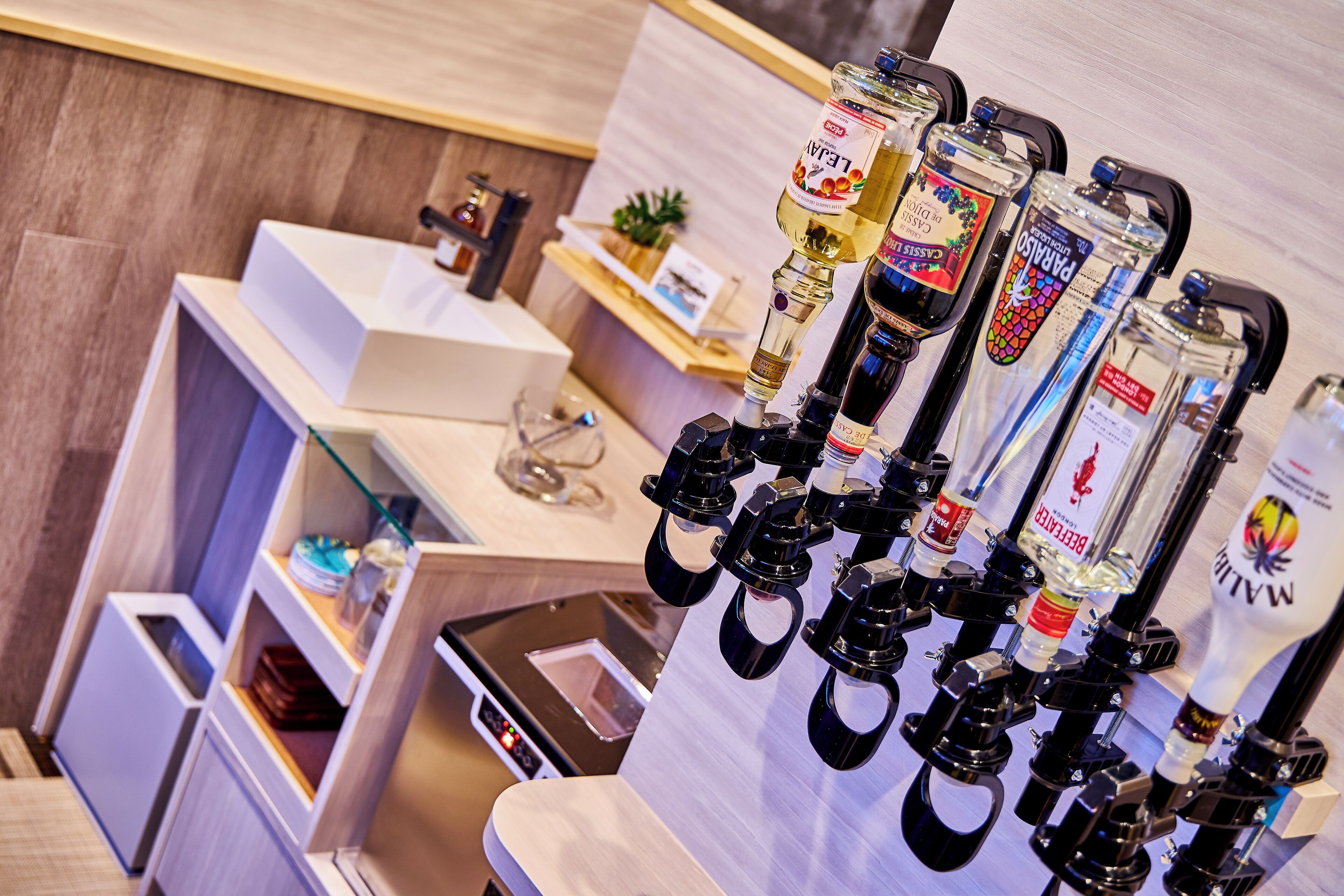 A bar area with multiple liquor dispensers, a small reception desk, and a plant on the counter.