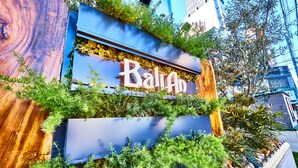 Un letrero de hotel con el nombre "BaliAh" y una estructura de madera con vegetación.