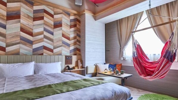 Una habitación de hotel moderna con una cama grande, una hamaca colgante y vistas de la ciudad.