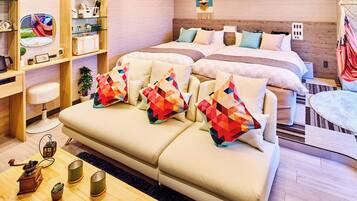 Ein modernes Hotelzimmer mit einer Couch, einem Bett, einem Schreibtisch und einem kleinen Tisch mit einer Kaffeemaschine.