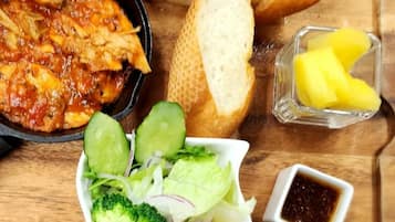 A meal with grilled chicken, bread, and a side salad.