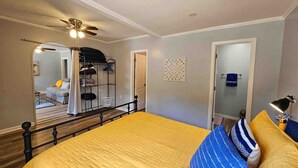 A bedroom with a bed, a ceiling fan, a door, and a mirror.