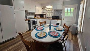 A modern kitchen with white cabinets, a central island, and a dining table set for four.
