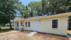 A single-story house with a front porch, a garage door, and a small front yard with a concrete path leading to the door.
