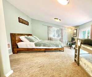A bedroom with a bed, a desk, a chair, a window with curtains, and a ceiling light. - Peaceful Forest Cottage with Hot Tub  Near Beach+Twin Rocks  Family&Pet Friendly (Rockaway Beach)