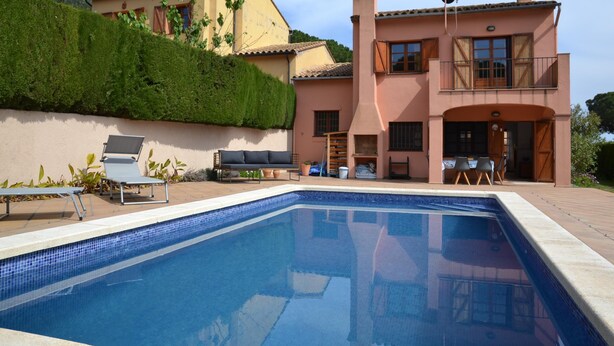 A pool area with lounge chairs and a patio table, surrounded by a landscaped garden and a two-story building with a balcony. - Sol i Vent - L'Estartit, Torre Vella (Estartit (L´))
