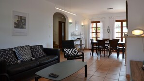 A living room with a black leather sofa, a coffee table, and a dining area with a table and chairs. - Sol i Vent - L'Estartit, Torre Vella (Estartit (L´))