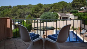 A balcony with two chairs and a table, overlooking a swimming pool and a lush green landscape. - Sol i Vent - L'Estartit, Torre Vella (Estartit (L´))