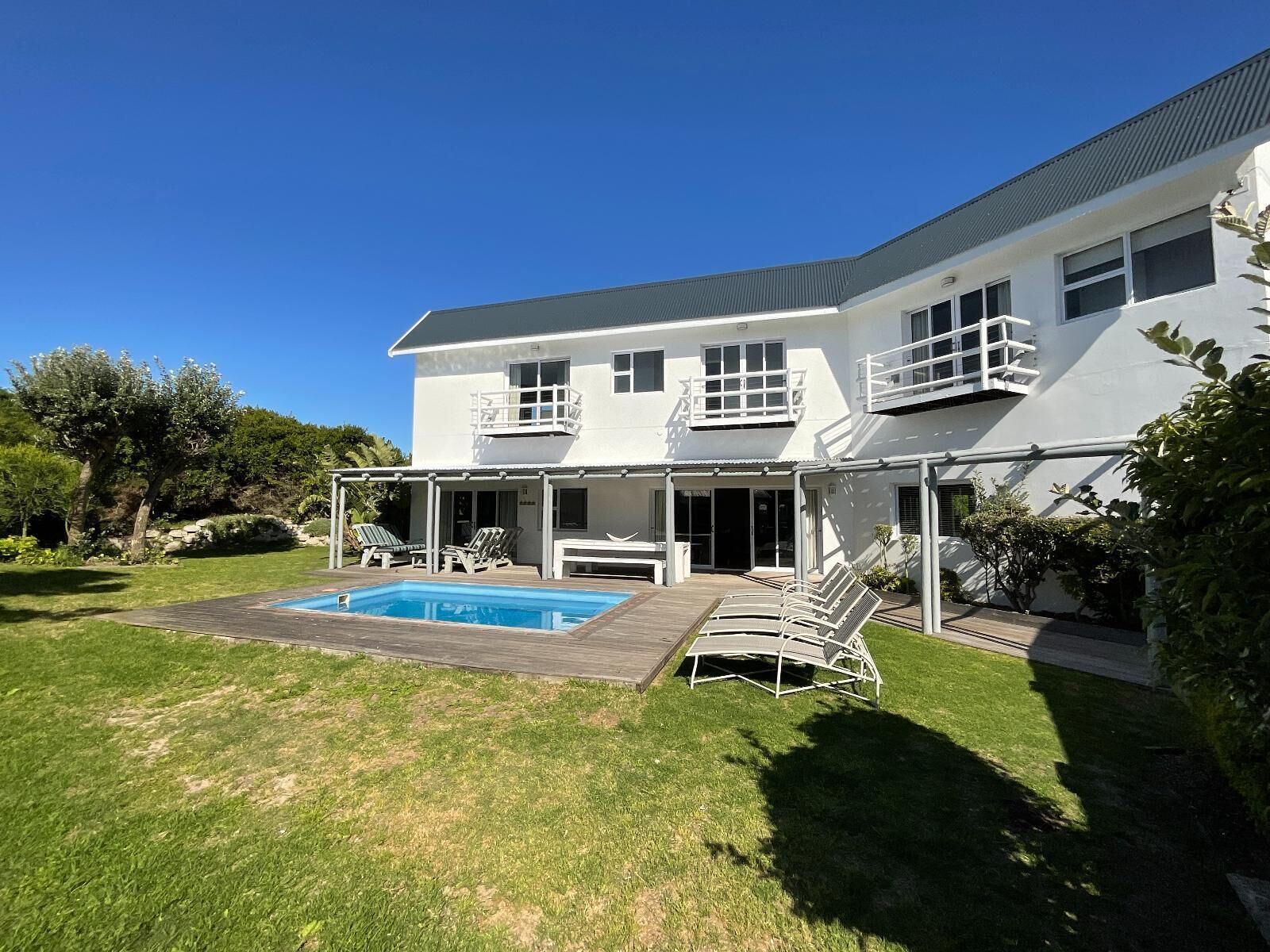 A two-story house with a swimming pool, outdoor seating, and a covered patio area.