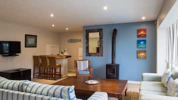 Una sala de estar con un sofá, una mesa de comedor, sillas, un televisor, una chimenea y obras de arte en la pared.