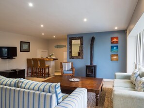 Ein Wohnzimmer mit einer Couch, einem Esstisch, Stühlen, einem Fernseher, einem Kamin und Kunstwerken an der Wand.