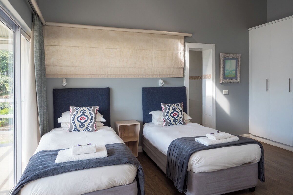 Une chambre d’hôtel avec deux lits, une grande fenêtre, une armoire et un miroir.