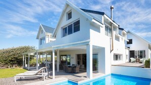 Une maison moderne à deux étages dotée d’une piscine, d’un espace salon extérieur et d’un patio couvert.