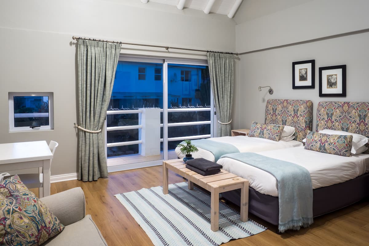 A bedroom with a bed, a desk, and a window with curtains.