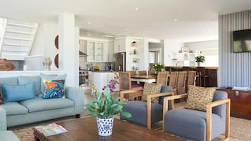 Una sala de estar moderna con un sofá, sillones, una mesa de centro y un comedor con mesa y sillas.