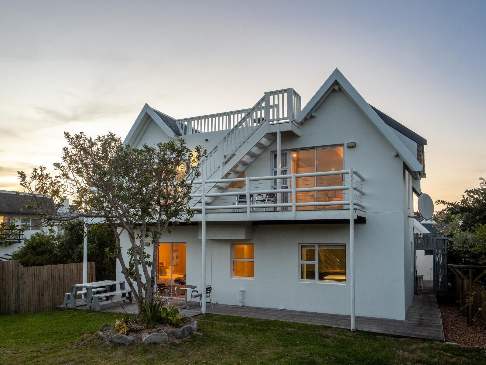 A two-story house with a balcony, a wooden deck, and a small garden.