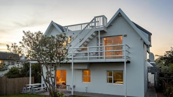 A two-story house with a balcony, a wooden deck, and a small garden.