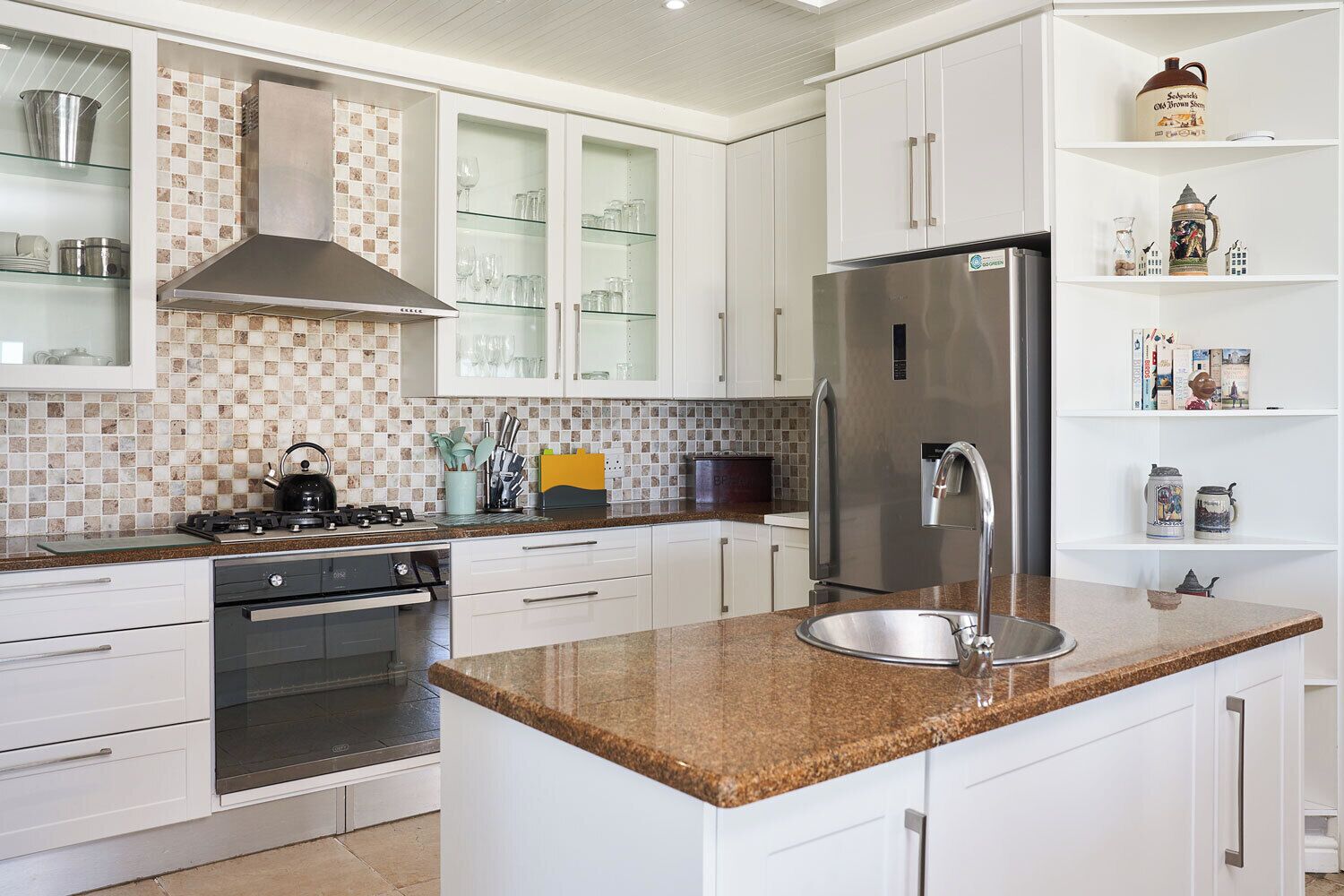 Una cocina moderna con armarios blancos, encimera de granito, electrodomésticos de acero inoxidable y salpicadero de azulejos.