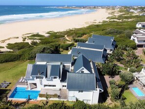 Une propriété située sur la côte, comprenant plusieurs maisons, une piscine et offrant une vue sur la plage.