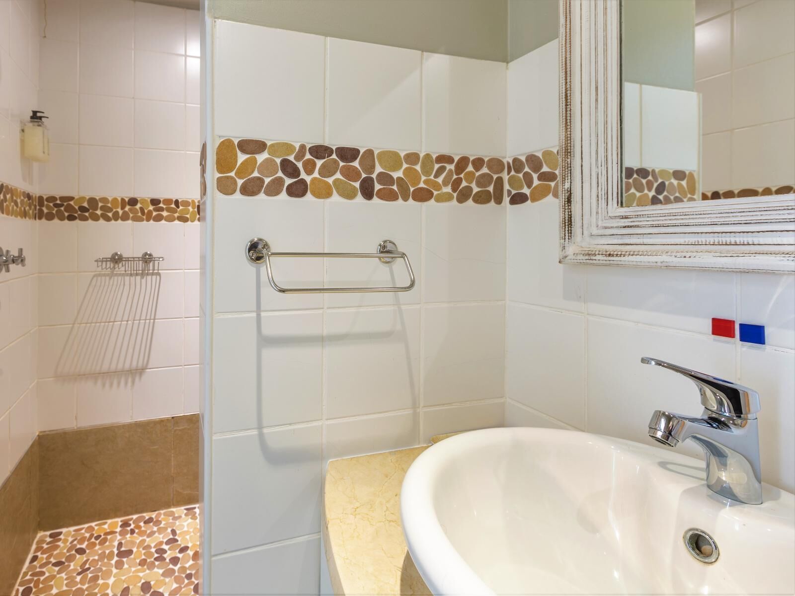 Ein Badezimmer mit Dusche, Waschbecken und Spiegel.