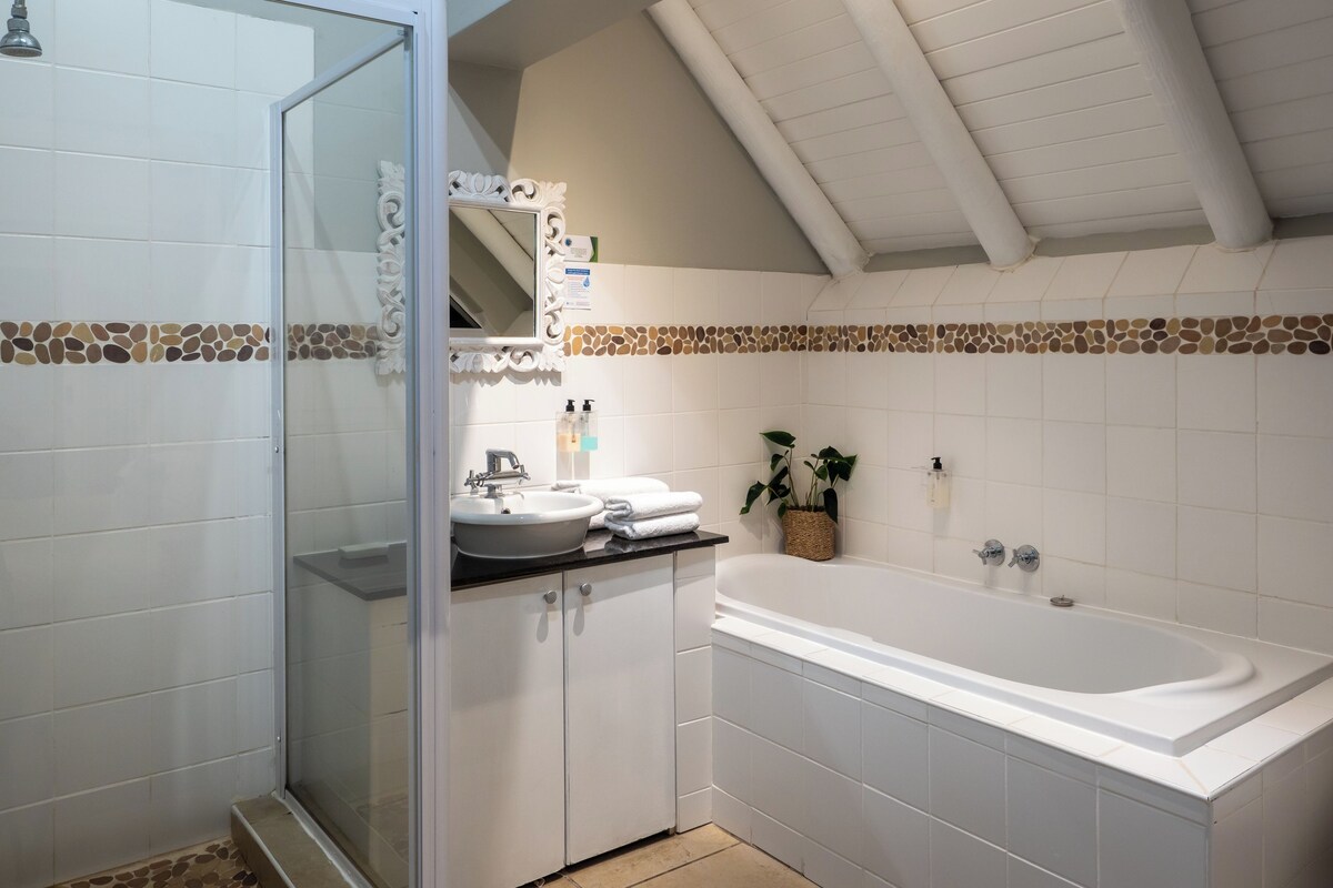 A bathroom with a shower, a sink, a bathtub, and a mirror.